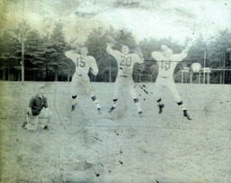 Coach Ferzacca (kneeling) ca. 1960: Coach Ferzacca Kneeling Next to Players #15, #20, and #19 Who Are Throwing Footballs