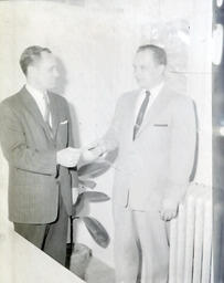 Dr. Embree and Melvin (?) Scholarship from Marquette - Alger County Distributors Association: Brighter Photo of One Man Handing Something to Another Man