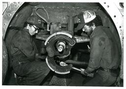 Two Students Working Inside Large Circular Machine (Part of the NMU Historic Photographs Collection)