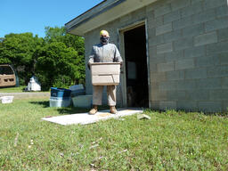 Man Holding Tub of Documents outside Painesdale Mine and Shaft Block Building