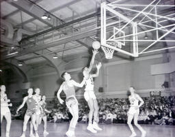 Basketball--NMC vs. St. Norbert Feb. 24, 1961: College Basketball Players Jumping with Ball by Net