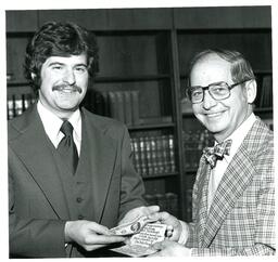 Student Receiving Dollar Bill from John X. Jamrich for the Arts Chorale Cocktail-Dinner Benefit (Part of the NMU Historic Photographs Collection)