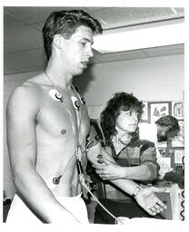 Woman Sets Up Vitals Monitor on Research Subject (Part of the NMU Historic Photographs Collection)