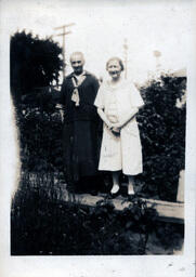 Two Older Women Stand in Garden