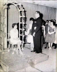 Queen Candidates--All-Events Weekend Feb. 23-25, 1961: Girl Sitting on Chair Next to Standing Man