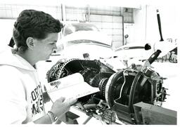 Student with Book Looking at Plane Engine (Part of the NMU Historic Photographs Collection)