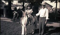 (008-022) Child, Pony, and Man Standing in Yard