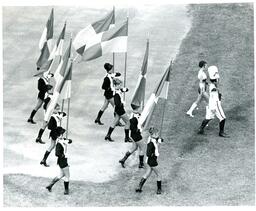 Drum Major and Flag Twirlers Marching on Dirt and Grass Field (Part of the NMU Historic Photographs Collection)