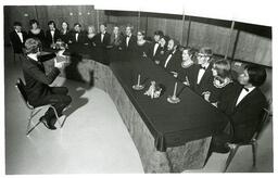 Choir in Matching Uniforms Singing while Sitting on Banquet Table (Part of the NMU Historic Photographs Collection)