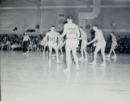 (128-05) Basketball NMC vs. Michigan Tech Feb. 24, 1960: Northern and Tech Players; Referee Looks On