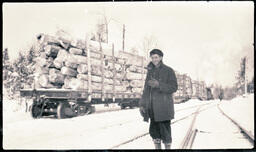 Man Posing in Front of Flatcars