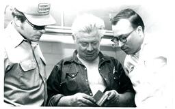 Gary Bell, Red Rackley, and Don Seagle Looking at Piece of Metal (Part of the NMU Historic Photographs Collection)