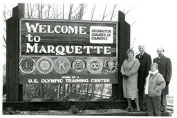 Four People Standing Next to Welcome to Marquette Sign (Part of the NMU Historic Photographs Collection)