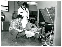 Two Students Rewiring Machine while Professor Watches (Part of the NMU Historic Photographs Collection)