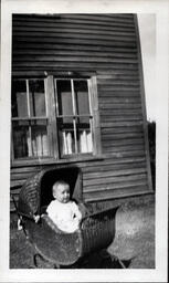 Baby in Wicker Buggy under Window