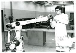 Student Using Screwdriver on Large Robotic Arm (Part of the NMU Historic Photographs Collection)