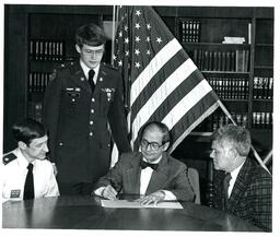 Jokinen and Two Other Men Watching John X. Jamrich Sign a Piece of Paper (Part of the NMU Historic Photographs Collection)