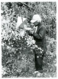 Man Looking at Piece of Paper in the Woods (Part of the NMU Historic Photographs Collection)