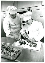 Professor Instructing Student Cutting Food (Part of the NMU Historic Photographs Collection)