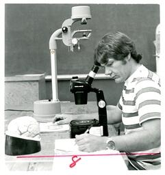 Student Looking at Specimen under Microscope (Part of the NMU Historic Photographs Collection)