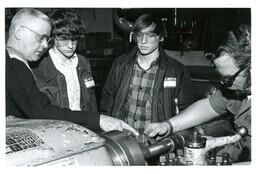 Man Pointing to Something on Machine as Another Man Works with Machine and Two Boys Watch (Part of the NMU Historic Photographs Collection)