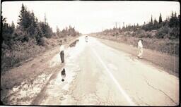 (024-003) Two Men Looking at Damage to M-64 after Flood