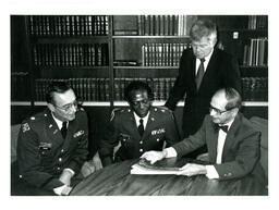 Smith, Taylor, John X. Jamrich, and Unknown Man Looking at Book (Part of the NMU Historic Photographs Collection)