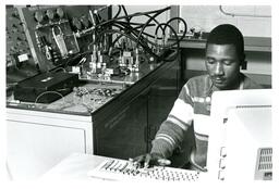 Student Typing on Computer next to 850 Controls Technology Training System (Part of the NMU Historic Photographs Collection)