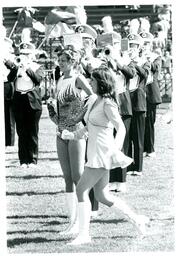 Color Guard Members in Short Dress and Leotard Standing in Front of Marching Band (Part of the NMU Historic Photographs Collection)