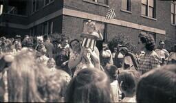 (008-028) Woman Holding Up Costumed Toddler for Crowd