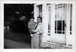 Man Holding Child in Police Cap