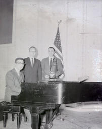 Senior Music Recitalists March 1961: One Man Sitting at Piano with Two Other Men