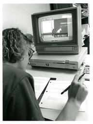 Student Writes Notes in Front of Computer Lab Simulation (Part of the NMU Historic Photographs Collection)