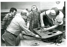 Four Men Taking Apart Car Door on Table (Part of the NMU Historic Photographs Collection)