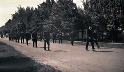 (008-039) Men in Military Uniforms Marching Down Dirt Road in Ontonagon Fourth of July Parade (2 of 2)