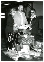 Three People Looking at Folder behind Machine (Part of the NMU Historic Photographs Collection)