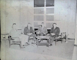 NMC Alumni Basketball 1960-61: Bad Photo of Four Men in Suits Sitting in Chairs