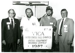 Four Men Posing with United States Skill Olympics Sign (Part of the NMU Historic Photographs Collection)