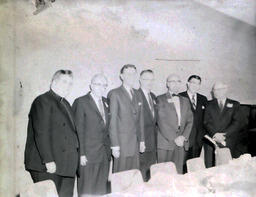 Superintendent and School Board Member Meeting 1961: Seven Men in Suits Lined Up by Wall