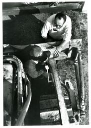 Overhead Shot of Two People Working on Construction Machine (Part of the NMU Historic Photographs Collection)