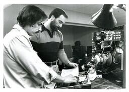 Two Men Looking at Paper next to Electronic Machine (Part of the NMU Historic Photographs Collection)