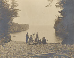 People on stony beach (view from shore)