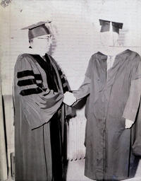 Commencement--Dr. Harden and Gunther Meyland Jan. 1961: Two Men in Graduation Gowns Shaking Hands by Window