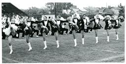 Cheerleaders Doing Kick Line in Front of Marching Band (Part of the NMU Historic Photographs Collection)