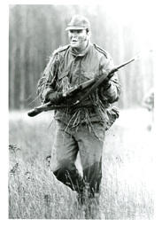 Man in Military Uniform Covered in Grass and Holding Gun Running through Field (Part of the NMU Historic Photographs Collection)