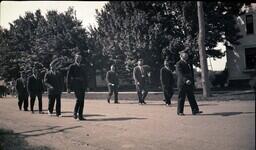 (008-037) Men in Military Uniforms Marching Down Dirt Road in Ontonagon Fourth of July Parade (1 of 2)