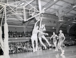 NMC Basketball--Aquinas Basketball 1960-61: Basketball Players Reaching for Basketball by Net